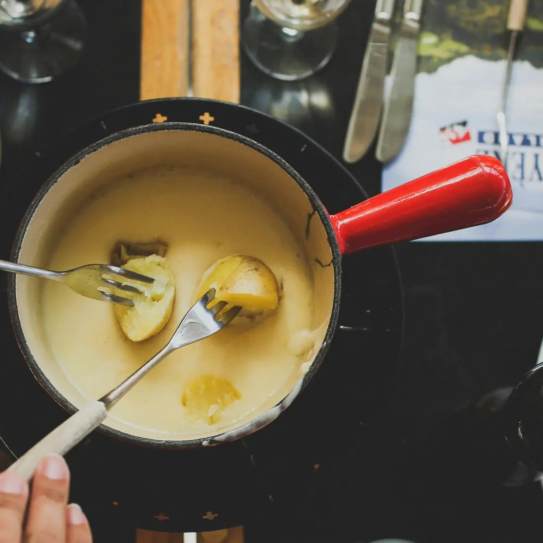 Caquelon di fonduta sul fornelletto, due forchette immerse nel formaggio